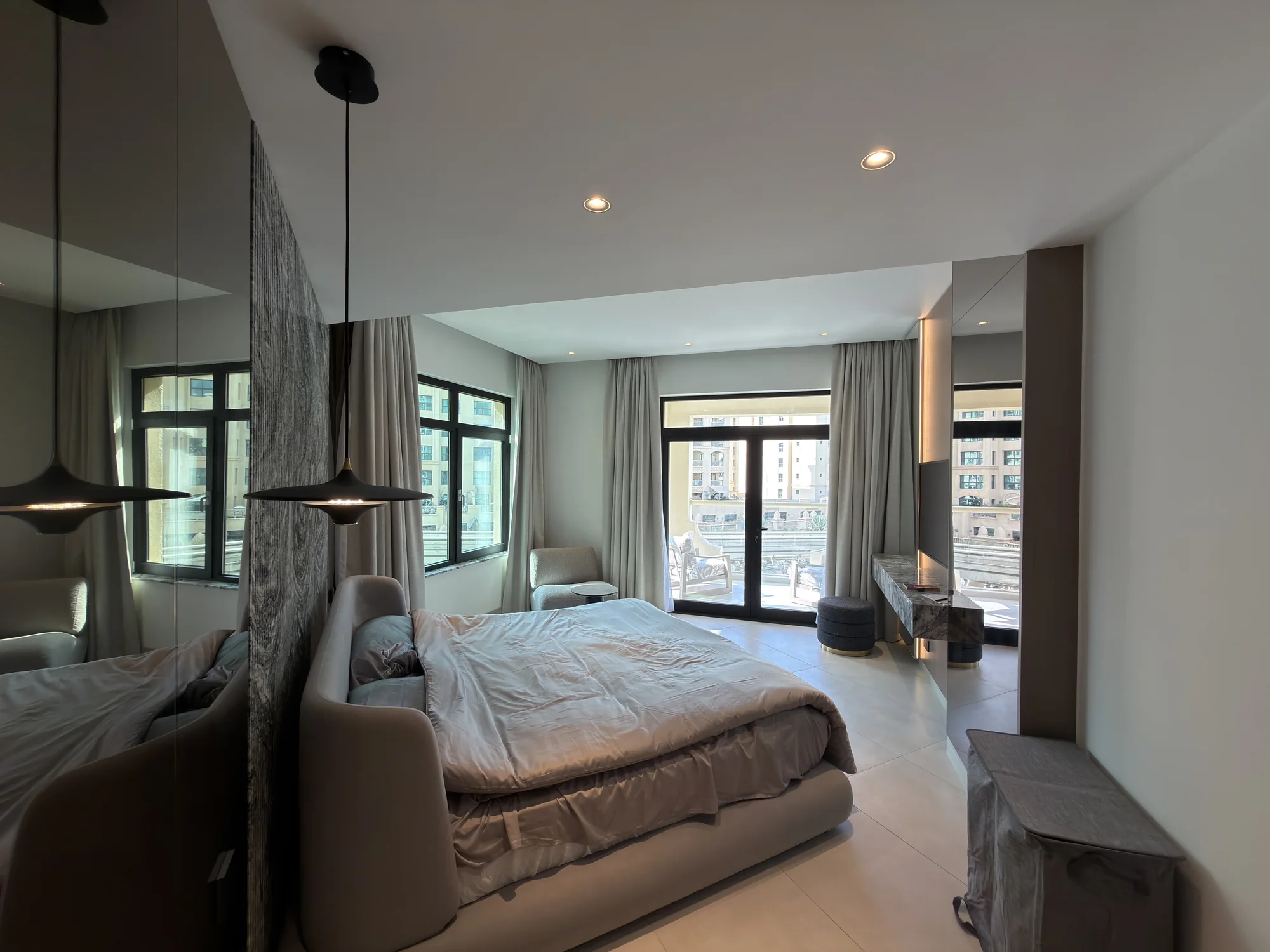 Bedroom interior with layered lighting and a wall-mounted control at the Shoreline residence